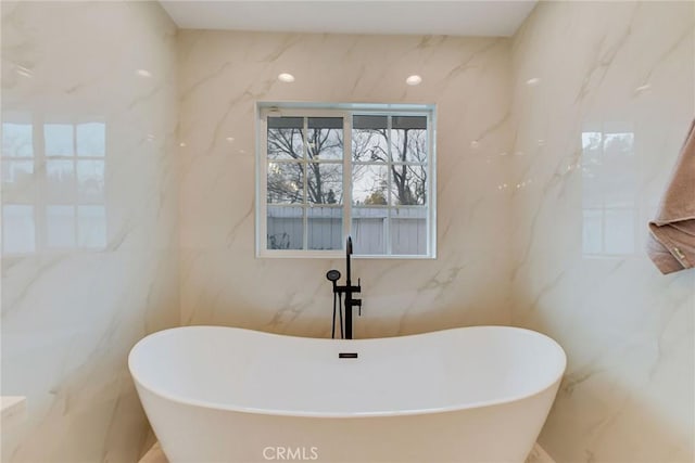 bathroom with a washtub and tile walls