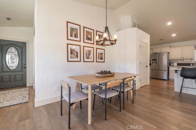 dining room with vaulted ceiling, an inviting chandelier, and light hardwood / wood-style floors