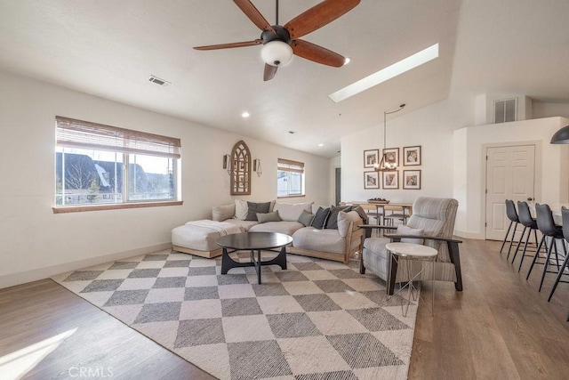 living room with a wealth of natural light, hardwood / wood-style floors, and vaulted ceiling with skylight