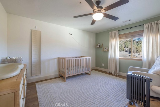 bedroom featuring ceiling fan, sink, hardwood / wood-style floors, and a crib