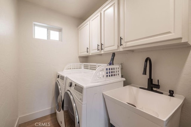 laundry area with sink, washing machine and clothes dryer, dark hardwood / wood-style floors, and cabinets