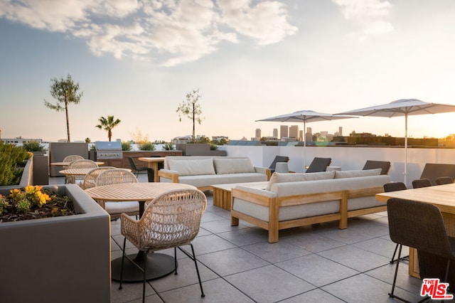 patio terrace at dusk featuring an outdoor living space, area for grilling, and a grill