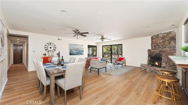 dining room with a stone fireplace and light wood-type flooring