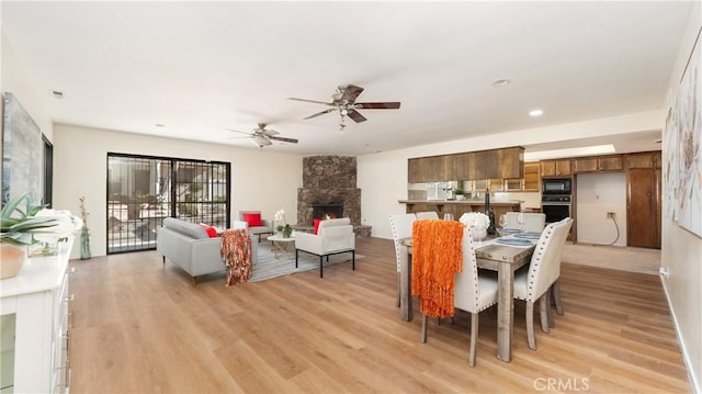 dining area featuring ceiling fan, light hardwood / wood-style flooring, and a fireplace