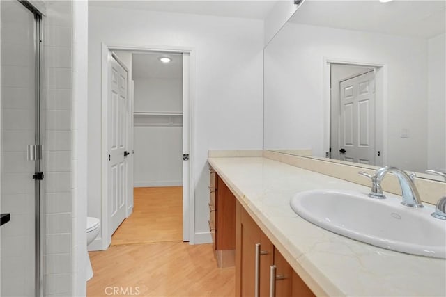 bathroom with vanity, toilet, hardwood / wood-style floors, and a shower with door