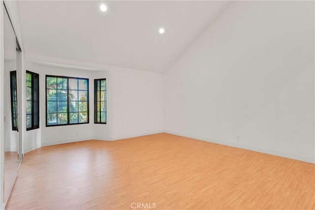 empty room with light wood-type flooring and lofted ceiling