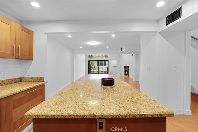 kitchen featuring light hardwood / wood-style floors, a center island, and light stone counters