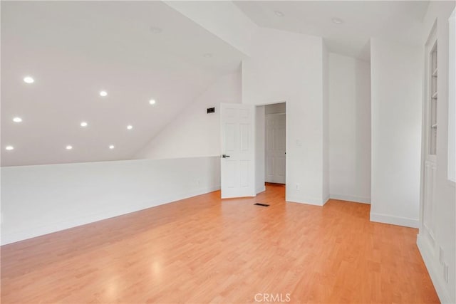 bonus room featuring light hardwood / wood-style floors, built in shelves, and vaulted ceiling