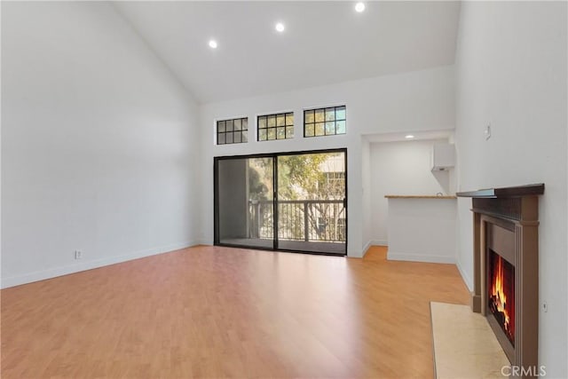 unfurnished living room with high vaulted ceiling and light hardwood / wood-style flooring