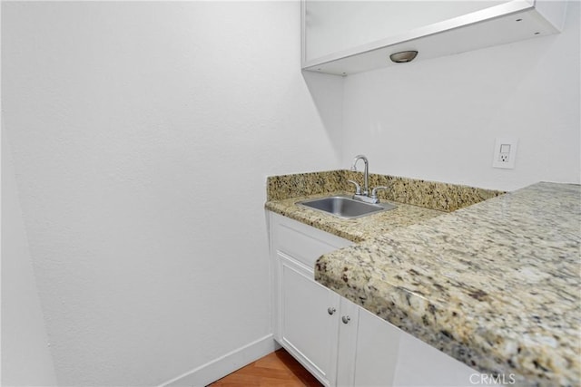 interior space with sink, light wood-type flooring, white cabinets, and light stone countertops