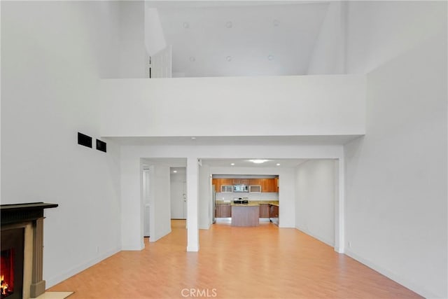 unfurnished living room with a high ceiling and light hardwood / wood-style flooring