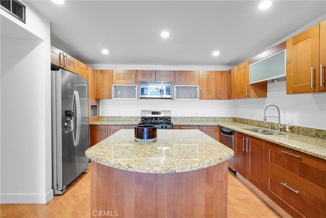 kitchen featuring sink, a center island, light stone counters, and appliances with stainless steel finishes