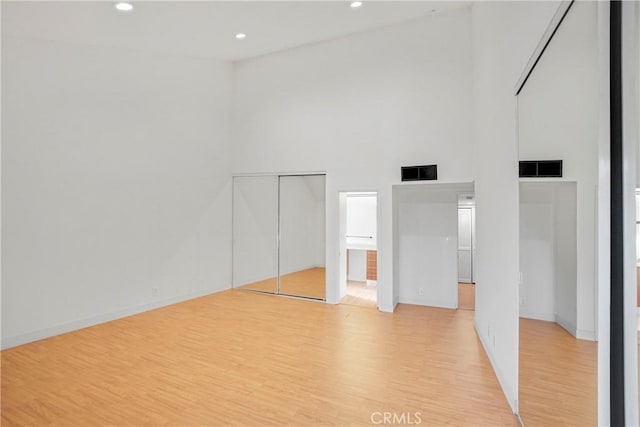 unfurnished bedroom with light wood-type flooring and a high ceiling