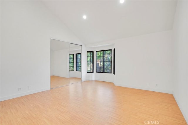 spare room featuring light wood-type flooring and high vaulted ceiling