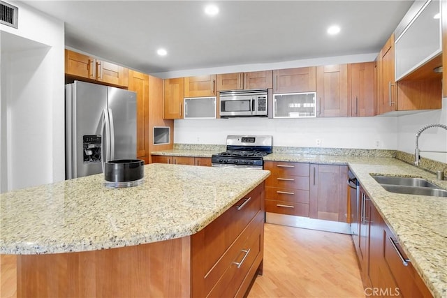 kitchen featuring light stone counters, sink, a center island, and stainless steel appliances