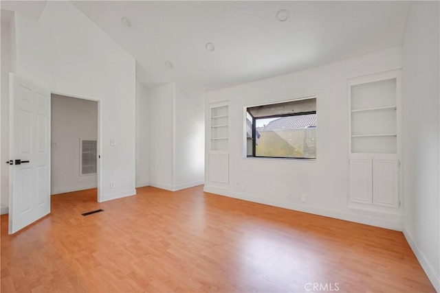 empty room featuring built in features and light hardwood / wood-style flooring