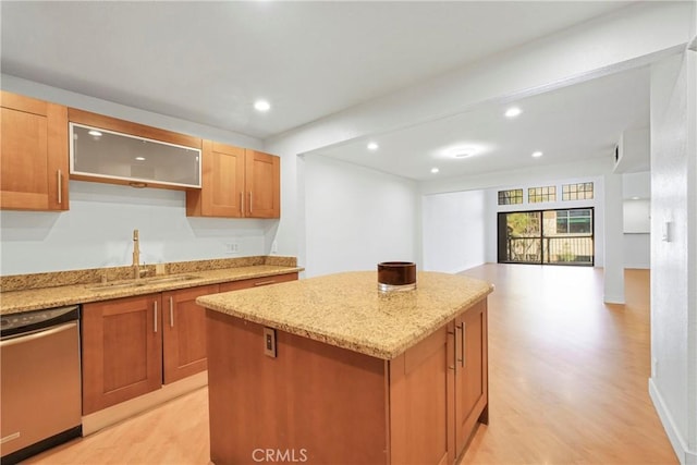 kitchen with light stone countertops, dishwasher, a center island, sink, and light hardwood / wood-style flooring