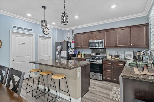 kitchen featuring pendant lighting, appliances with stainless steel finishes, dark stone counters, and a kitchen island