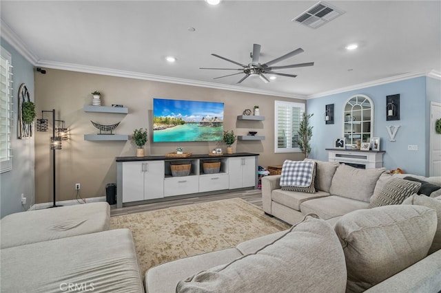 living room with hardwood / wood-style flooring, ceiling fan, and ornamental molding