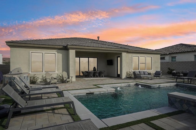 back house at dusk with a fenced in pool and a patio