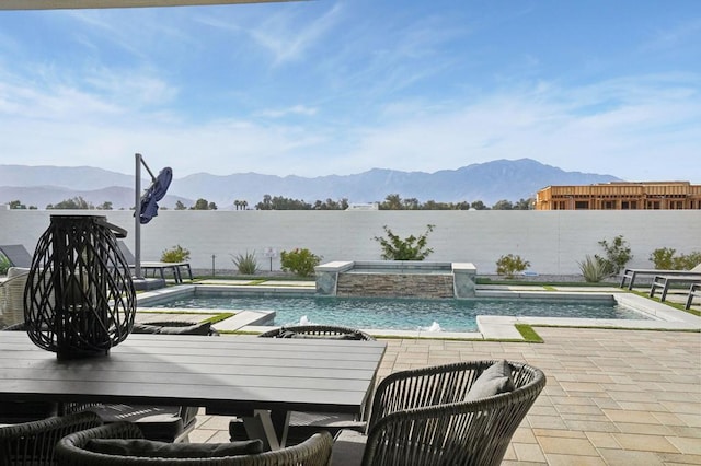 view of pool with an in ground hot tub, pool water feature, a water and mountain view, and a patio