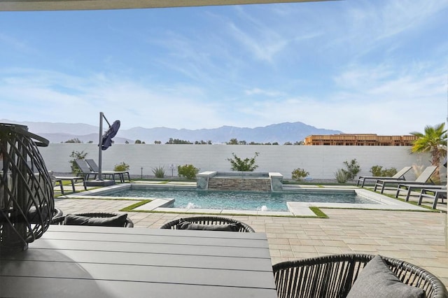 view of swimming pool featuring a patio, a mountain view, pool water feature, and an in ground hot tub