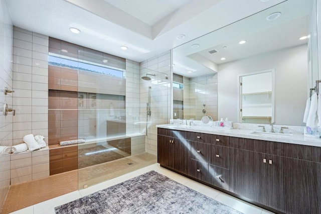 bathroom featuring tile patterned flooring, vanity, and a tile shower