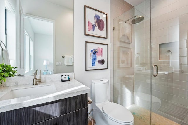 bathroom featuring vanity, a shower with shower door, and toilet