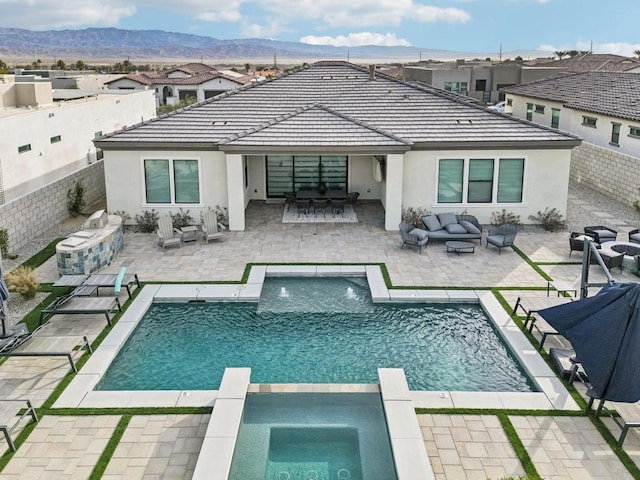 back of property featuring a mountain view, a pool with hot tub, a bar, an outdoor living space, and a patio