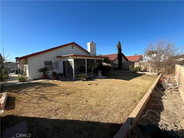 rear view of property featuring a sunroom and a lawn