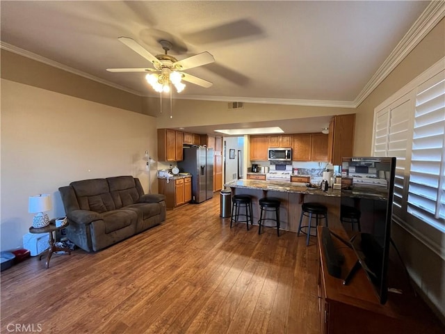 living room featuring hardwood / wood-style floors, vaulted ceiling, ceiling fan, and ornamental molding