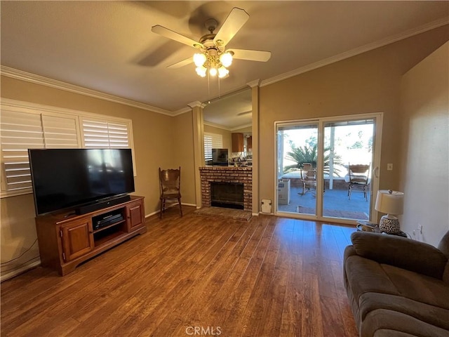 living room with hardwood / wood-style floors, a fireplace, vaulted ceiling, ceiling fan, and crown molding