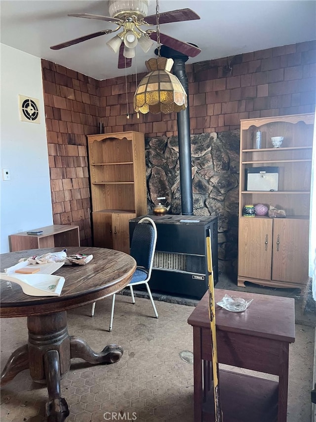 carpeted dining room featuring a wood stove and ceiling fan