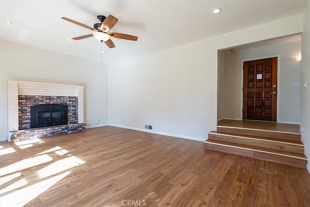 unfurnished living room with a fireplace, wood-type flooring, and ceiling fan