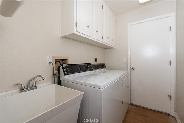 washroom with dark hardwood / wood-style flooring, sink, washer and clothes dryer, and cabinets