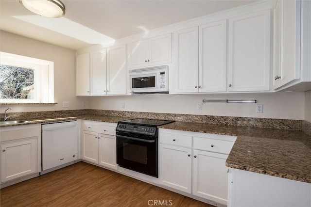 kitchen with white cabinetry, hardwood / wood-style floors, and white appliances