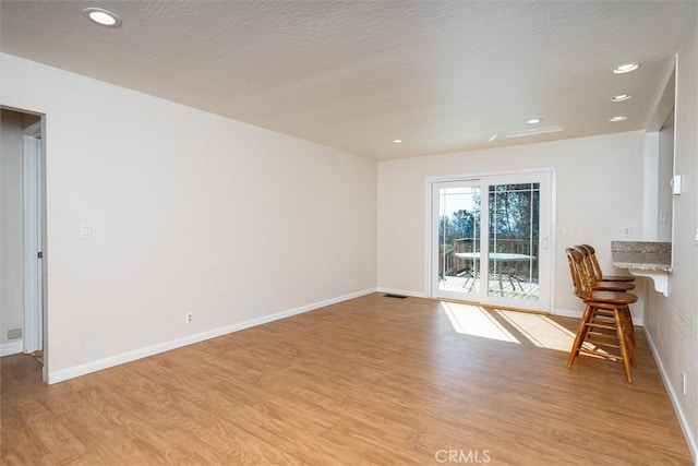 unfurnished living room featuring a textured ceiling and light hardwood / wood-style floors