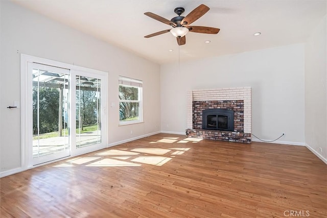 unfurnished living room with a brick fireplace, ceiling fan, and light wood-type flooring