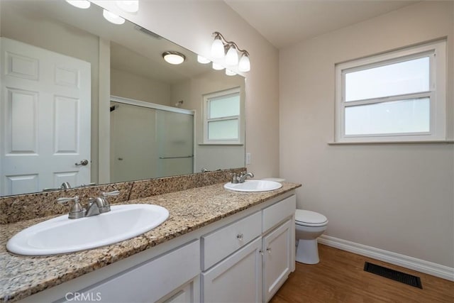 bathroom with vanity, hardwood / wood-style flooring, a shower with shower door, and toilet