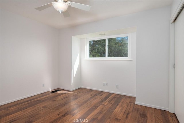 spare room with dark wood-type flooring and ceiling fan