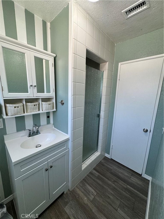 bathroom with vanity, walk in shower, hardwood / wood-style floors, and a textured ceiling