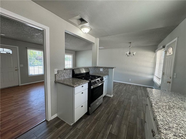 kitchen with light stone counters, white cabinets, dark hardwood / wood-style floors, and stainless steel gas range oven