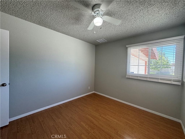 unfurnished room with ceiling fan, wood-type flooring, and a textured ceiling