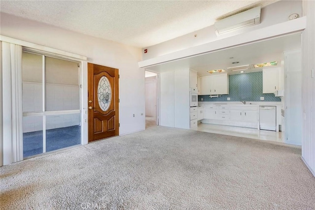 unfurnished living room with sink, light colored carpet, and a textured ceiling