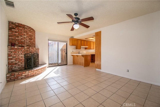 unfurnished living room with light tile patterned floors, a textured ceiling, a fireplace, and visible vents