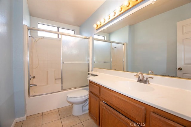 bathroom with combined bath / shower with glass door, vanity, toilet, and tile patterned floors