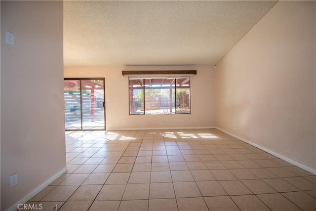 spare room with light tile patterned floors, a textured ceiling, and baseboards