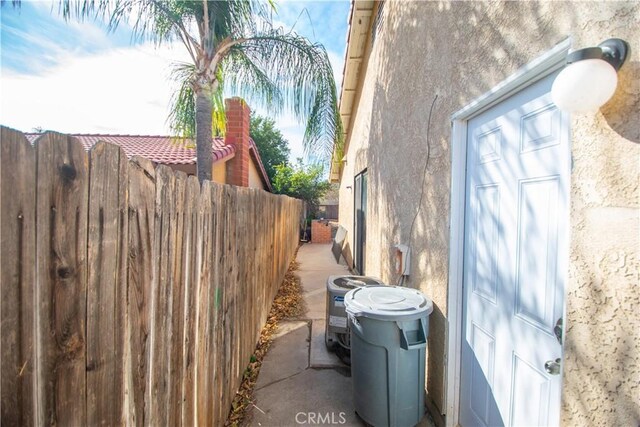 view of side of property featuring central air condition unit, fence, and stucco siding