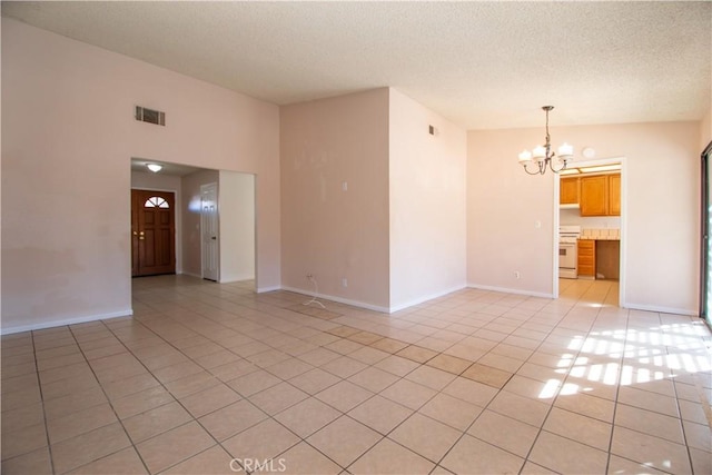 spare room with visible vents, a notable chandelier, a textured ceiling, and light tile patterned floors