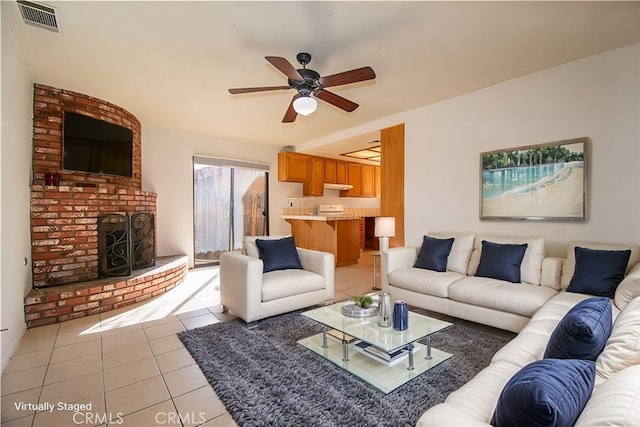 living room featuring a brick fireplace, ceiling fan, visible vents, and light tile patterned flooring